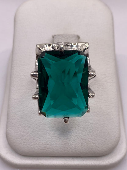 Anillo de plata solitario con circonia verde teal en la mano de una mujer