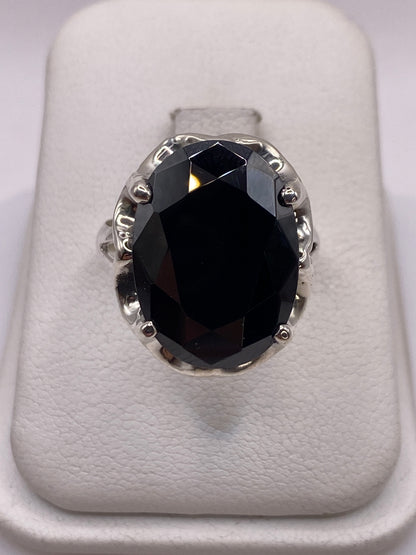 Anillo solitario de plata con circonia negra facetada frente a la cámara