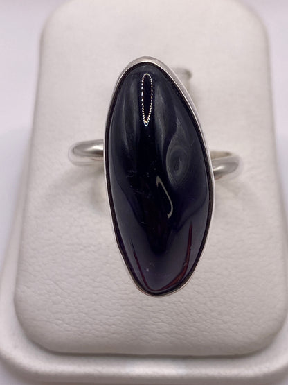 Anillo ajustable de plata con piedra morada natural pulida en la mano de una mujer