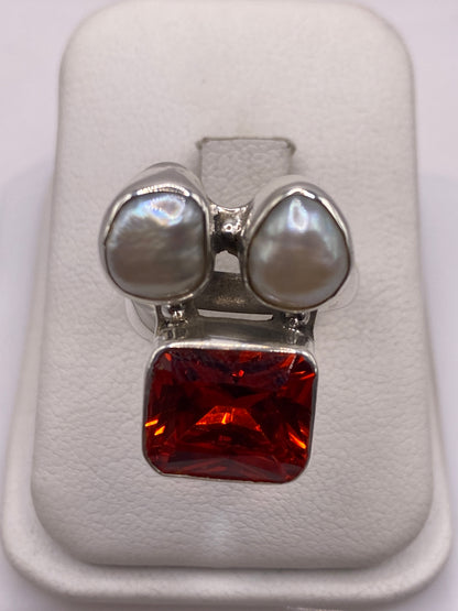 Anillo ajustable de plata con circonia naranja fuego y dos perlas blancas en caja de presentación