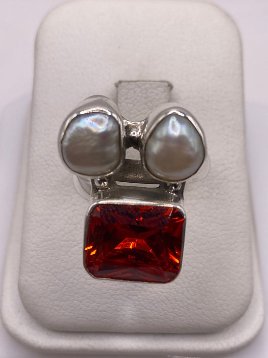 Anillo ajustable de plata con circonia naranja fuego y dos perlas blancas en caja de presentación