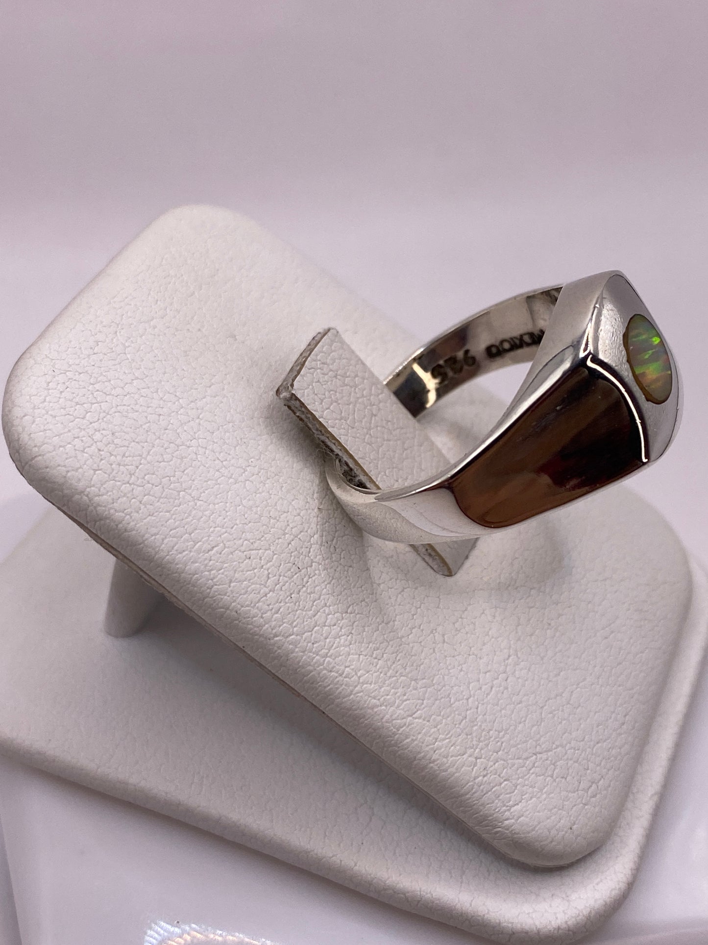 Anillo ópalo de fuego en mano mostrando juego de colores amarillo, naranja y rojo