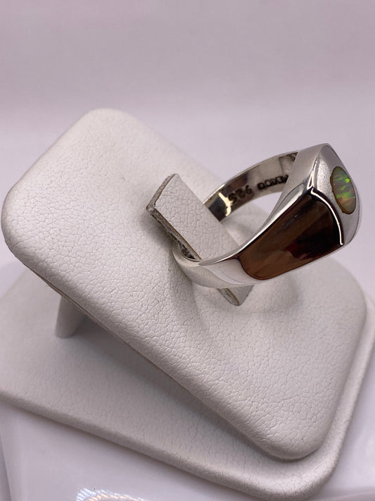 Anillo ópalo de fuego en mano mostrando juego de colores amarillo, naranja y rojo