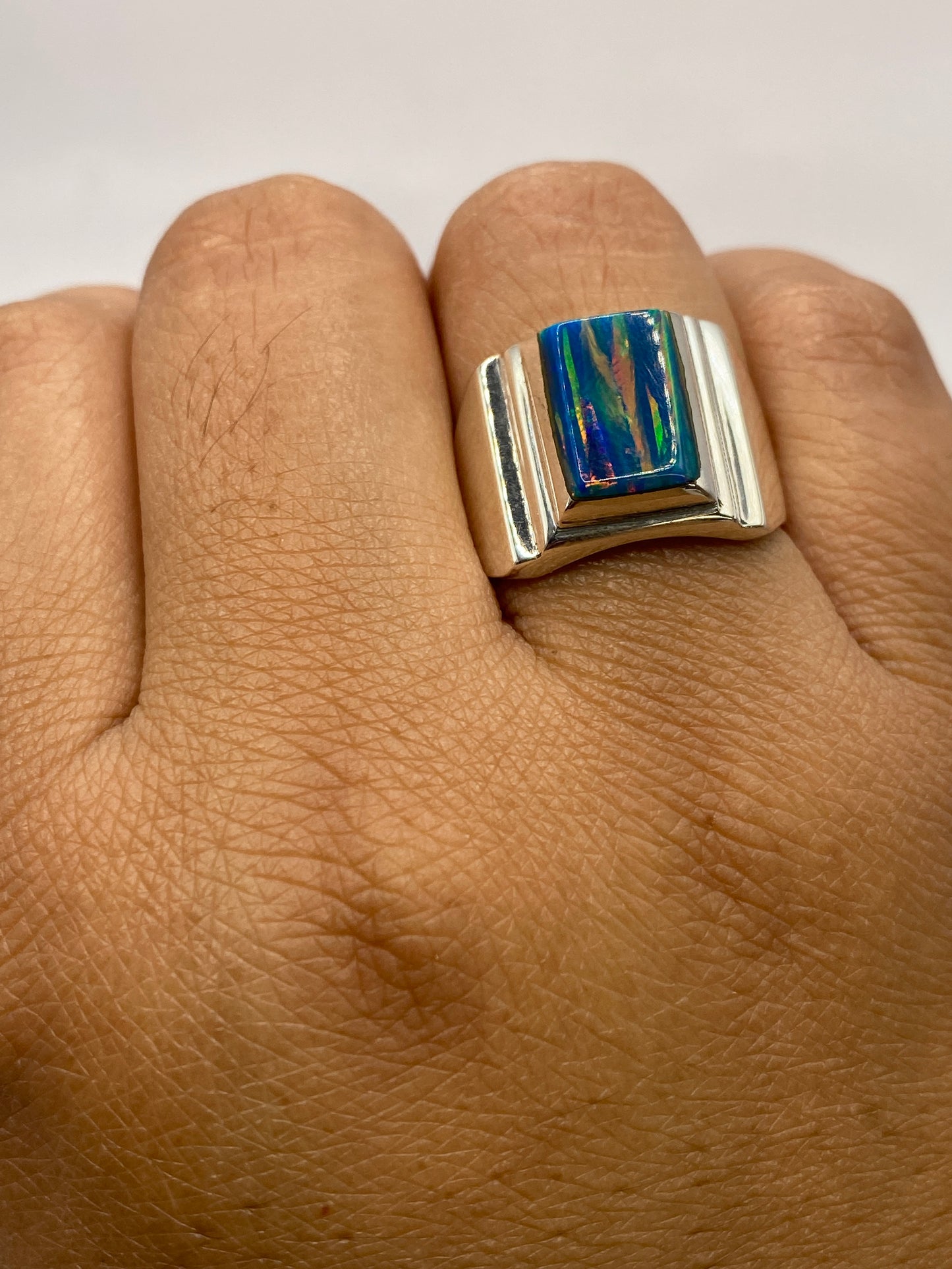 Anillo en la mano mostrando el sello 925 MEXICO y el brillo natural del ópalo