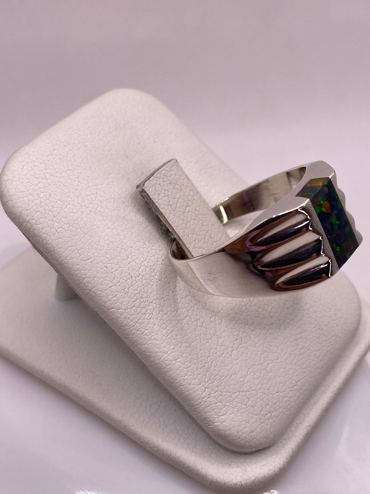 Anillo con alas talladas abrazando piedra ópalo de fuego, vista lateral en plata