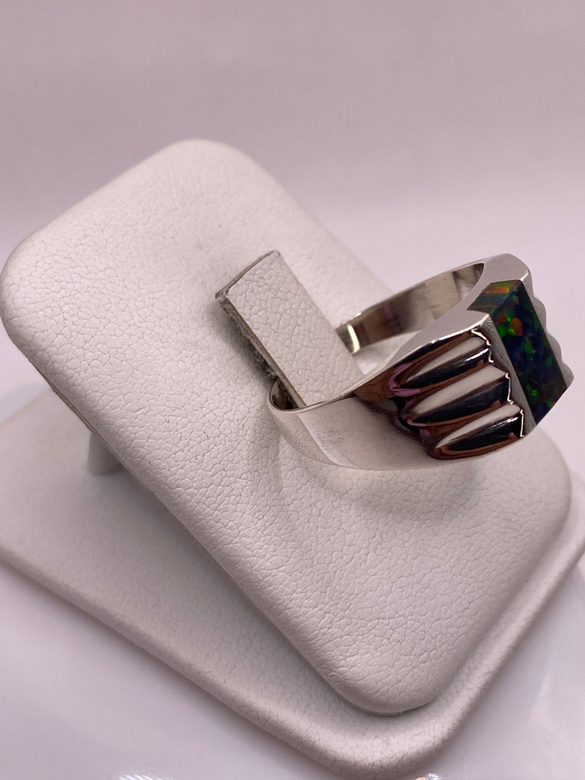 Anillo con alas talladas abrazando piedra ópalo de fuego, vista lateral en plata