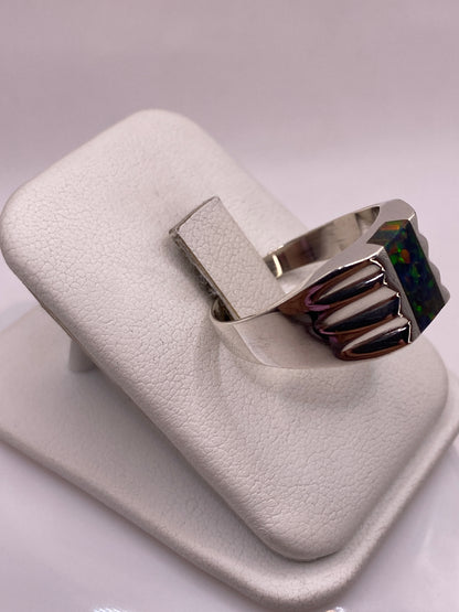 Anillo con alas talladas abrazando piedra ópalo de fuego, vista lateral en plata