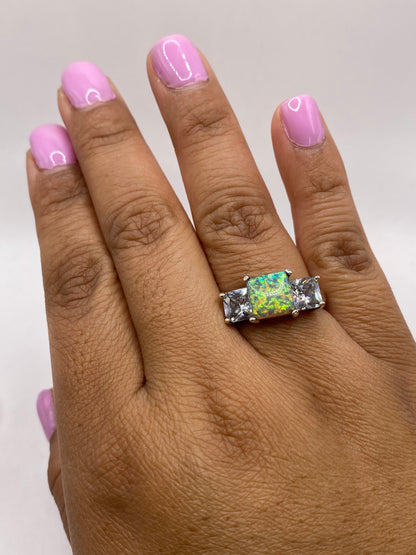 Anillo en dedo femenino con manicura rosa, mostrando el fuego del ópalo natural