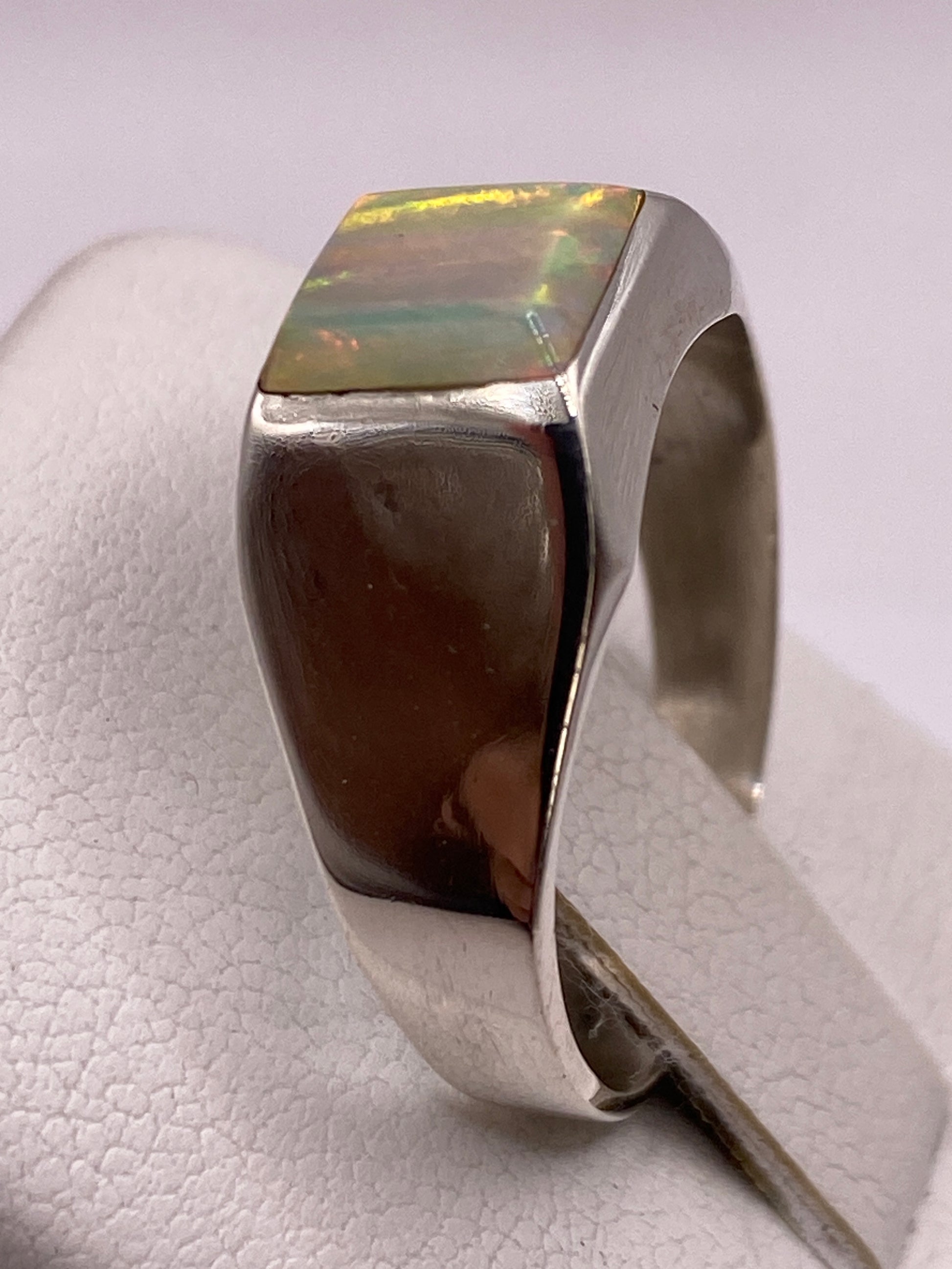Detalle lateral del anillo mostrando la piedra ópalo de fuego con su juego de colores único