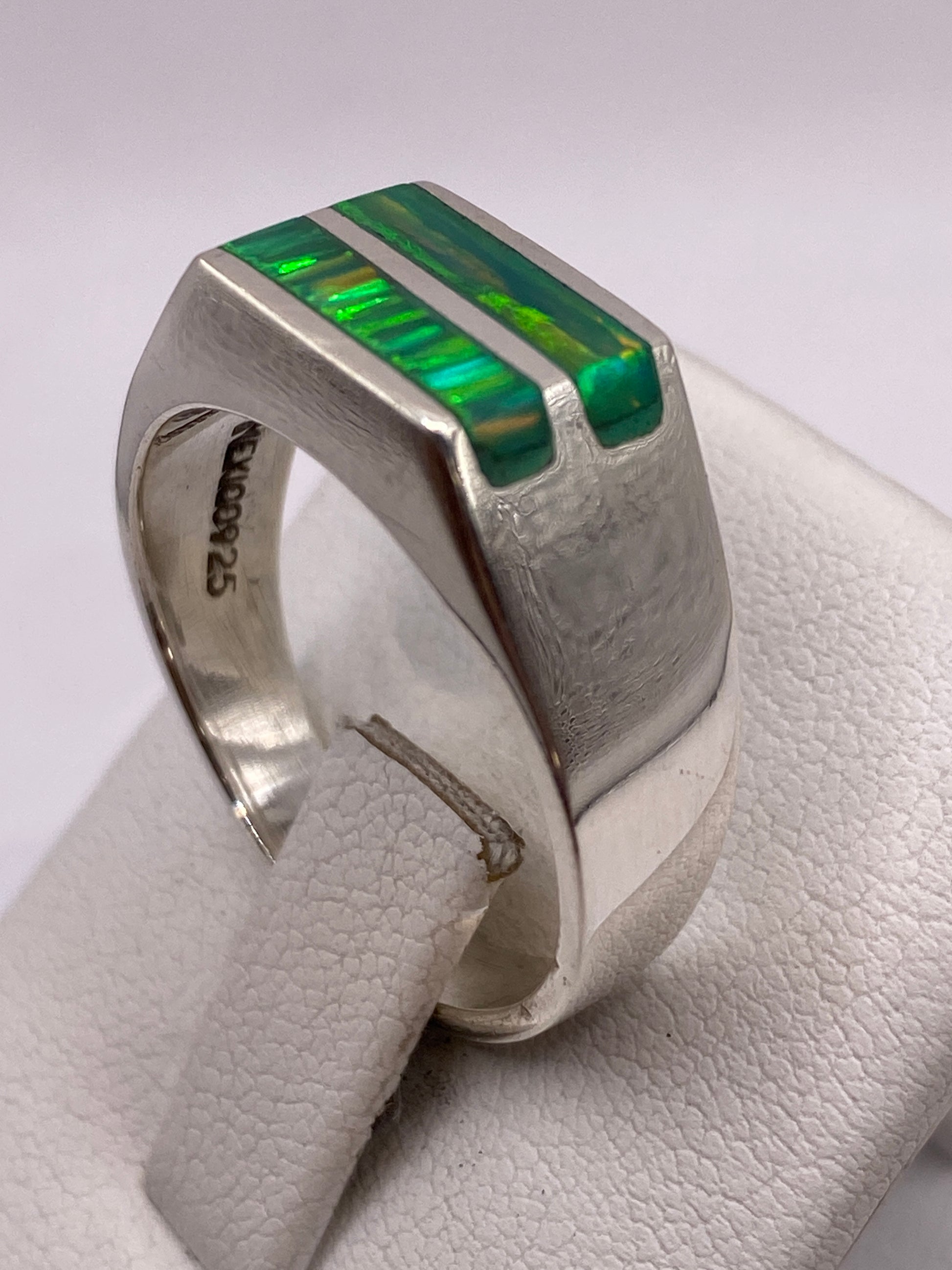 Anillo en mano de hombre mostrando el juego de colores verde y amarillo del ópalo