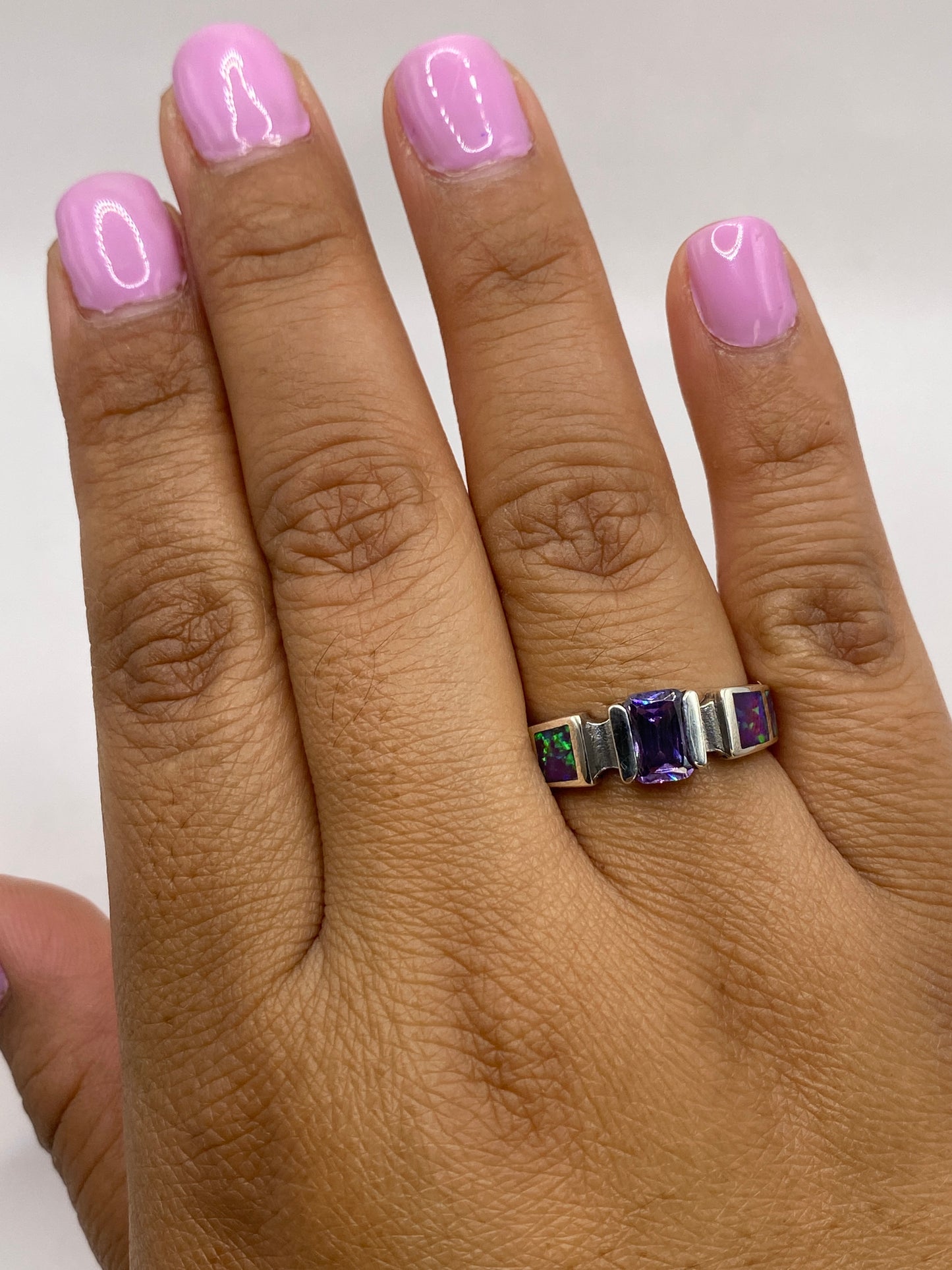 Anillo en dedo de mujer con esmalte rosa, mostrando el brillo del ópalo