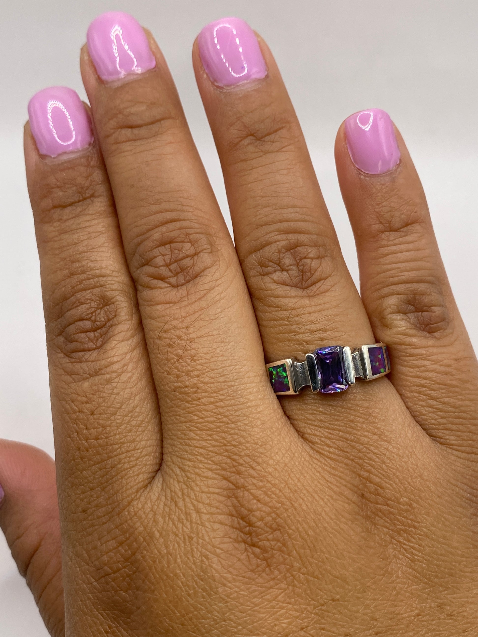 Anillo en dedo de mujer con esmalte rosa, mostrando el brillo del ópalo