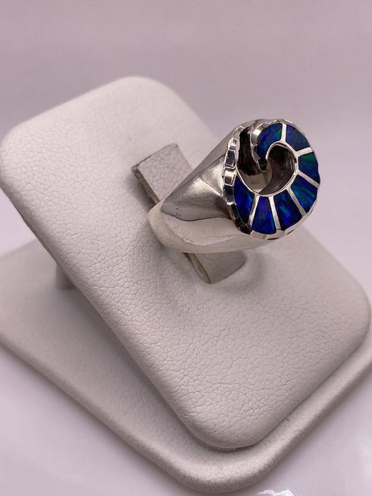 Anillo de plata .950 con ópalo de fuego azul en mano, mostrando el juego de colores