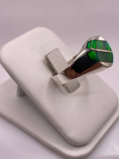 Detalle del ópalo de fuego mostrando juego de colores verde, azul y amarillo en anillo de plata