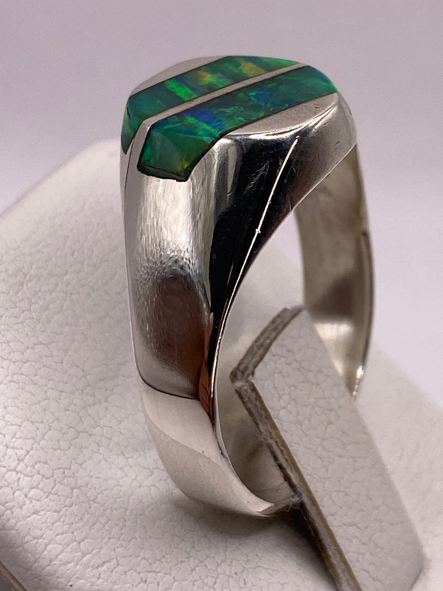 Anillo solitario ópalo fuego en dedo de hombre, vista frontal con luz natural
