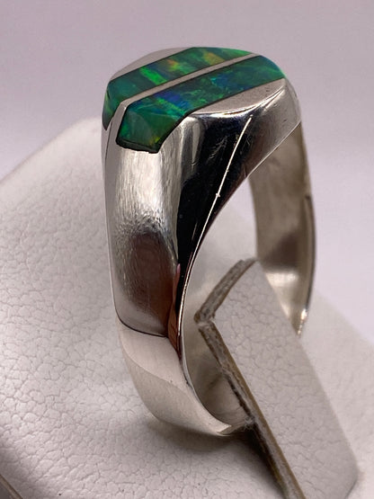 Anillo solitario ópalo fuego en dedo de hombre, vista frontal con luz natural