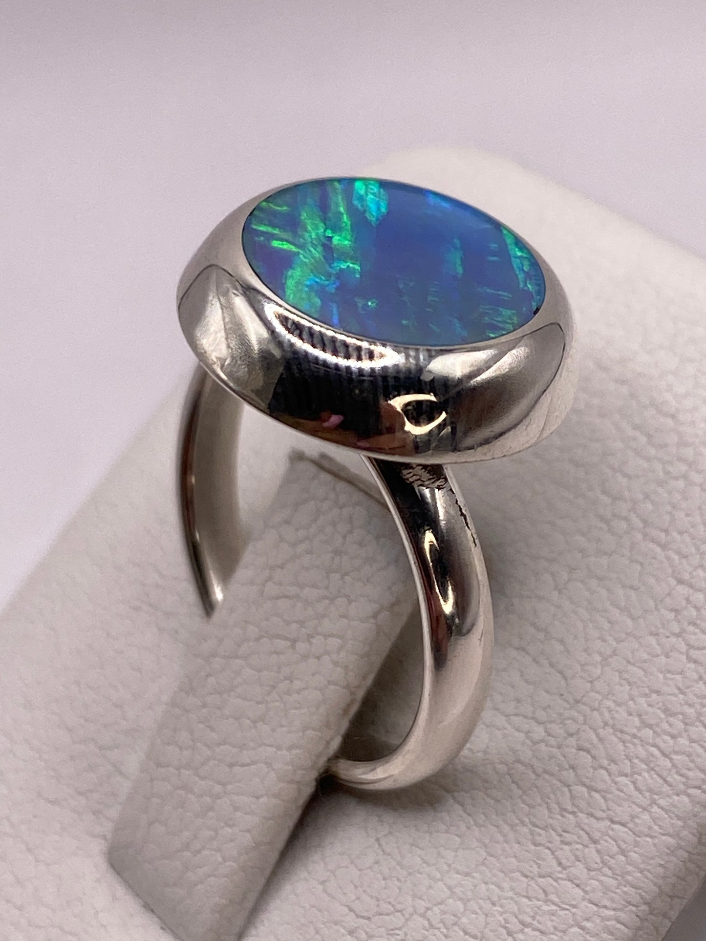 Anillo ajustable con ópalo natural azul cielo, vista lateral en dedo