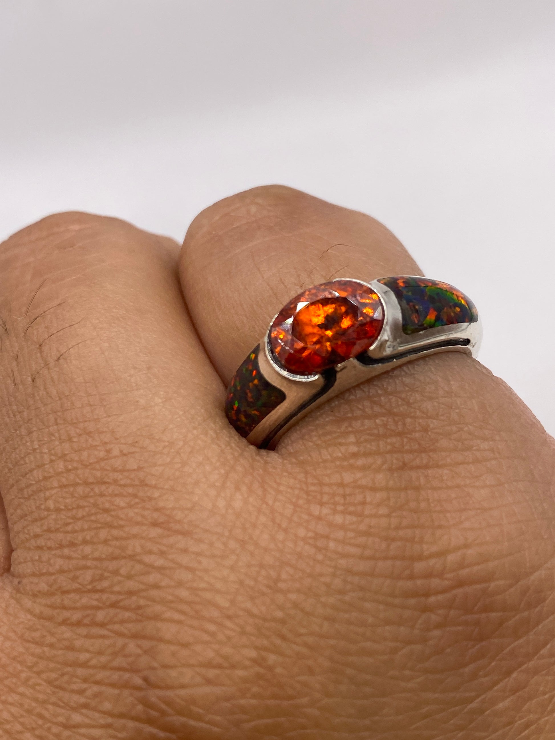 Anillo de ópalo de fuego en dedo, revelando los colores naturales multicolor bajo luz natural