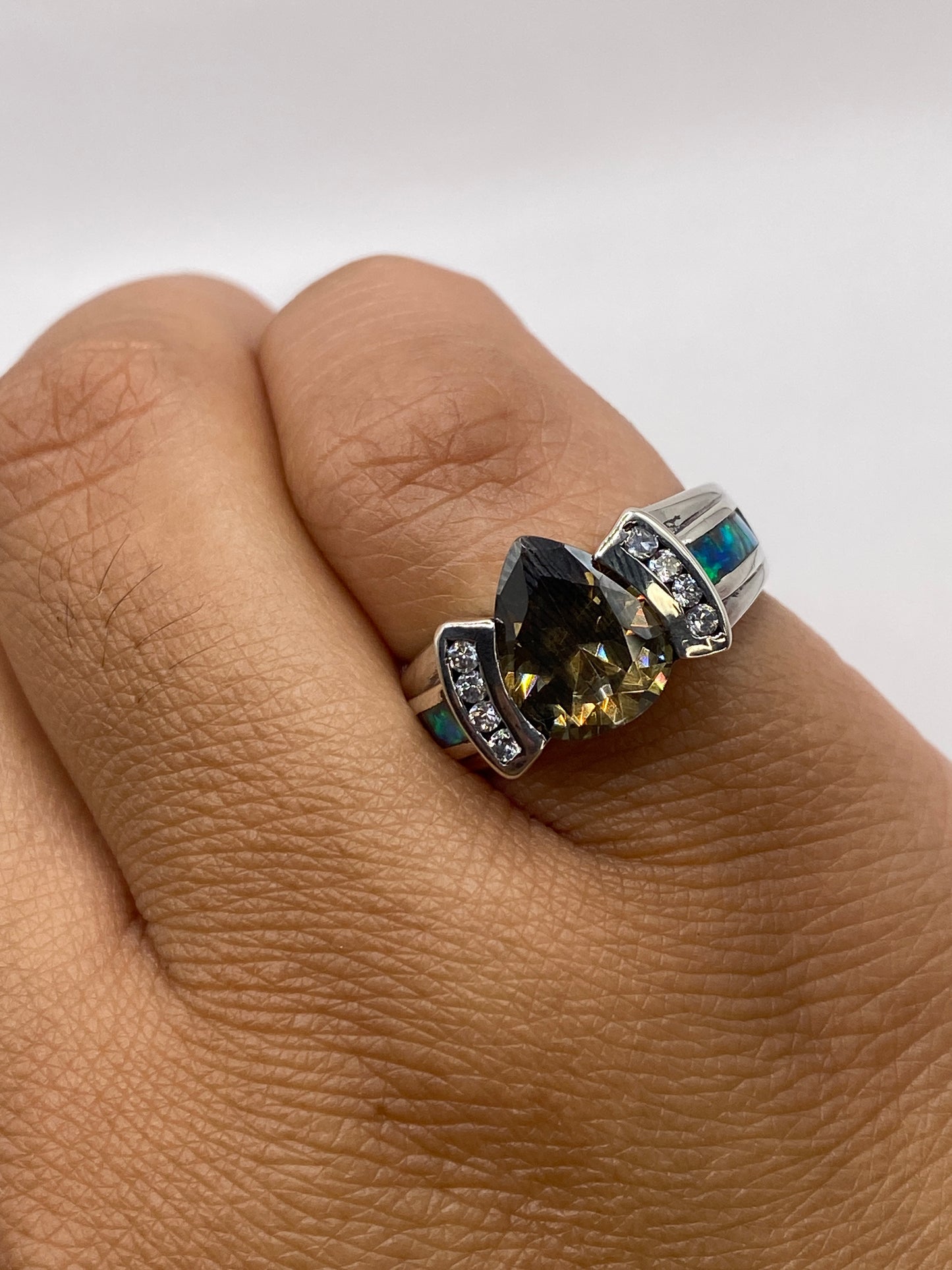 Anillo ópalo de fuego puesto en mano, mostrando juego de color natural verde y azul
