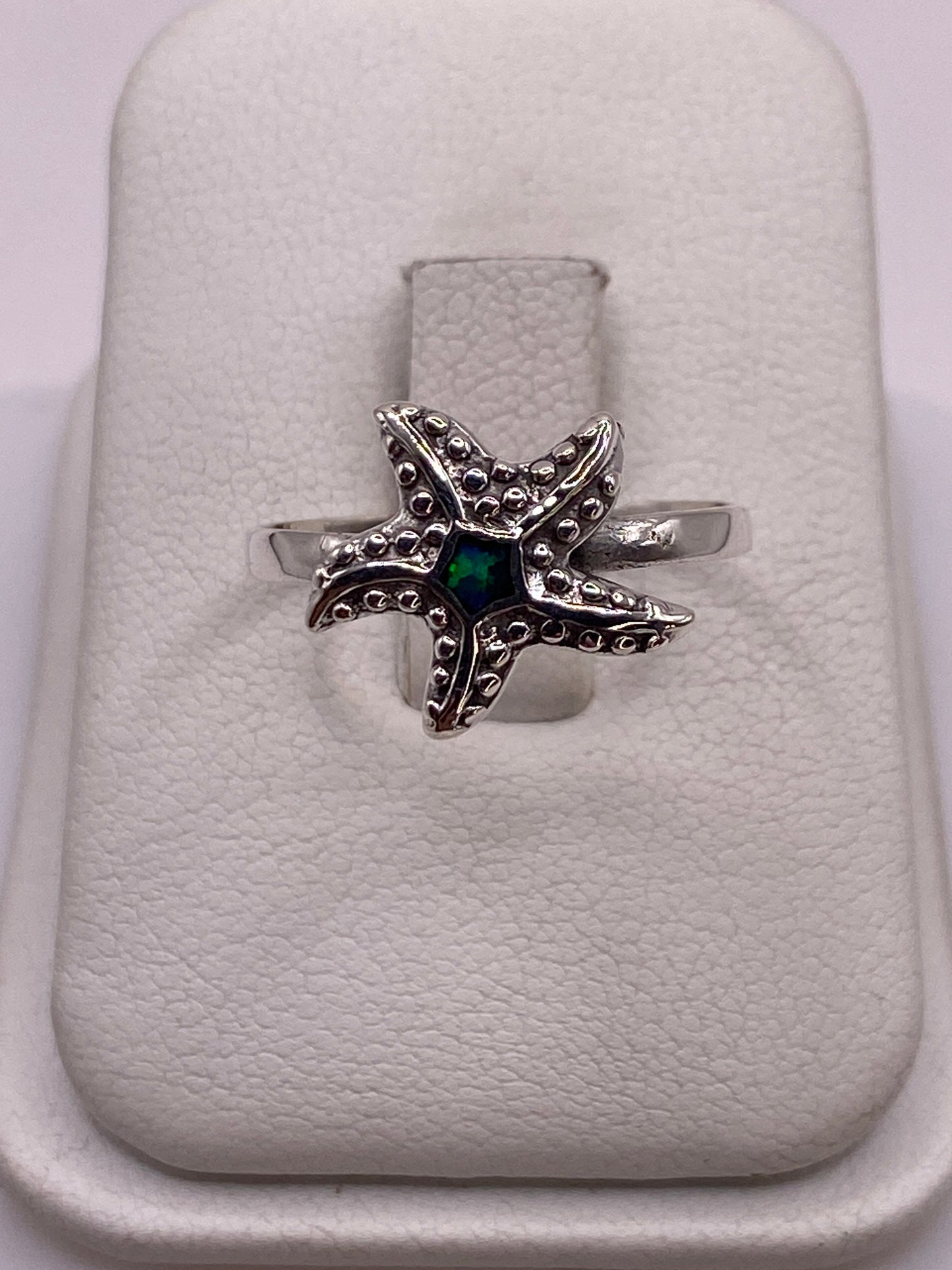 Anillo de plata estrella de mar con ópalo de fuego verde sobre estuche blanco