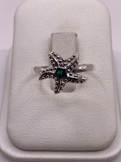 Anillo de plata estrella de mar con ópalo de fuego verde sobre estuche blanco