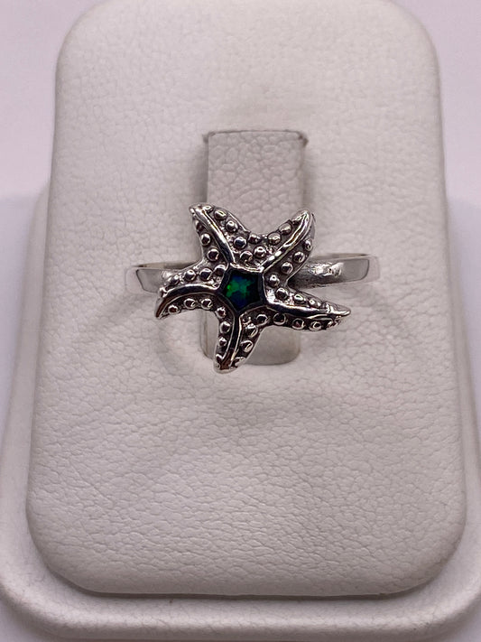 Anillo de plata estrella de mar con ópalo de fuego verde sobre estuche blanco