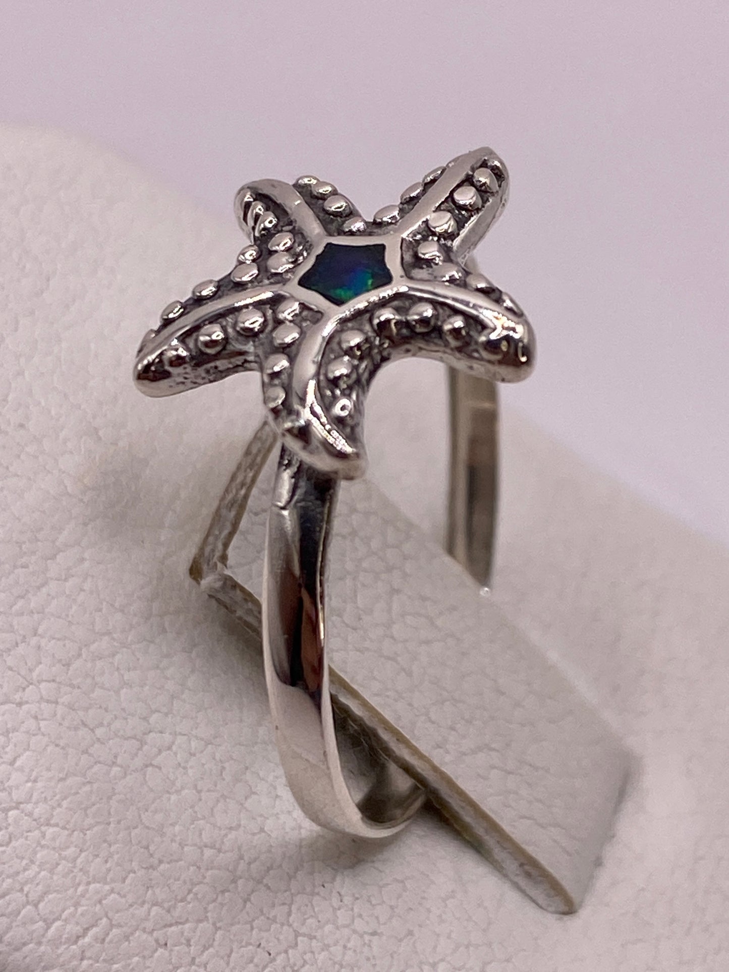 Anillo estrella de mar de plata .925 puesto en mano mostrando los reflejos del ópalo