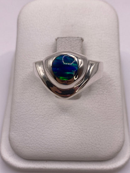 Anillo de plata .950 con ópalo de fuego azul natural, visto de frente sobre almohadilla blanca