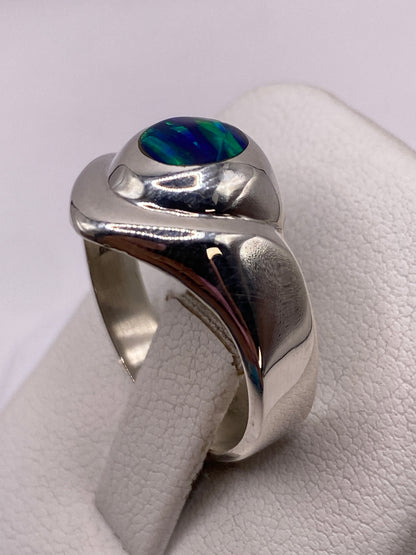 Detalle del ópalo de fuego con destellos azules, verdes y dorados en la mano