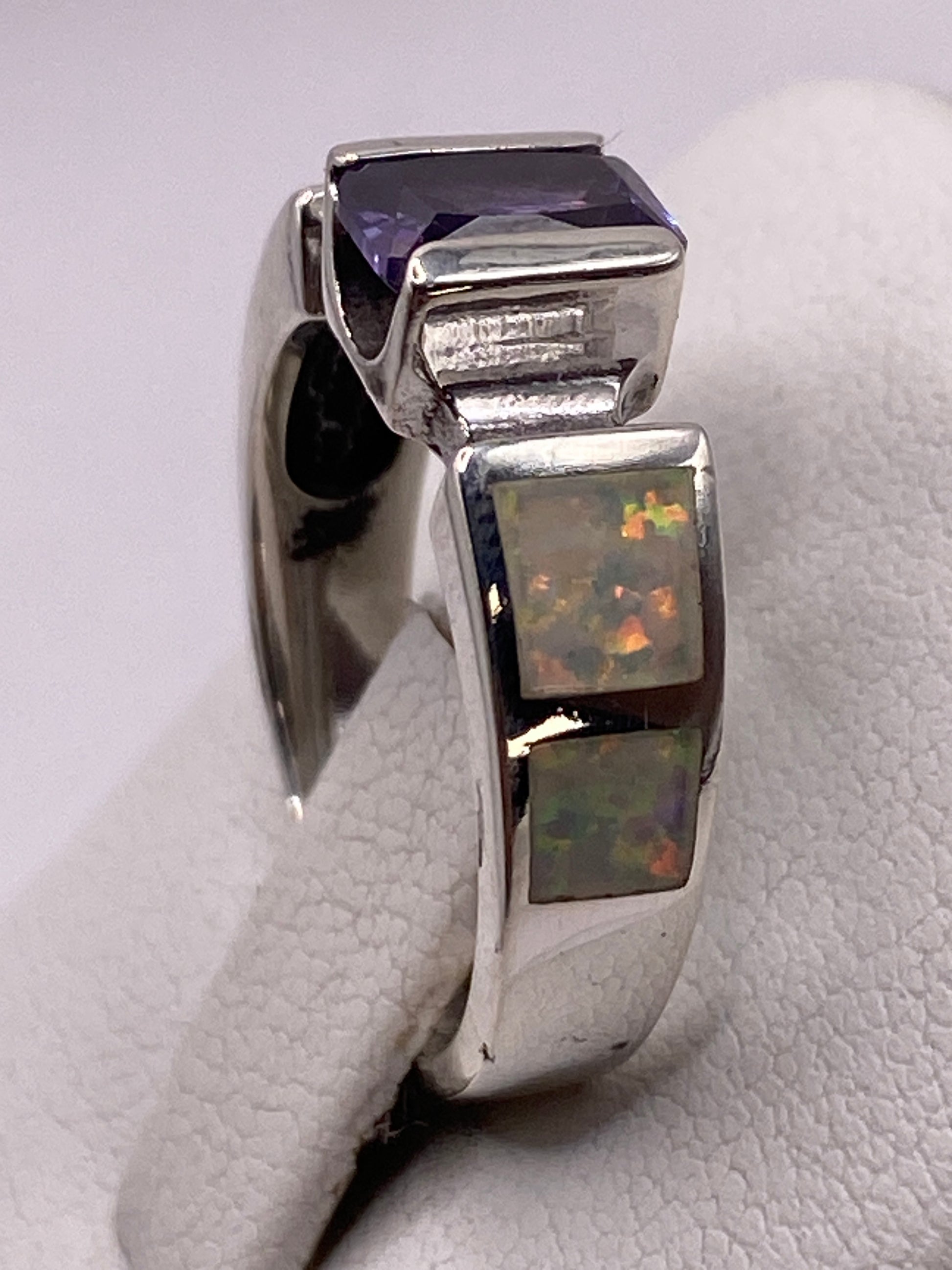 Anillo geométrico con ópalo en la mano de una persona, vista frontal
