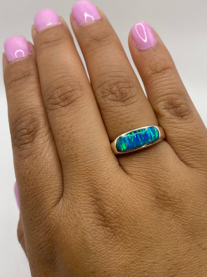 Anillo sobre dedo con nail art rosa, mostrando el fuego azul del ópalo