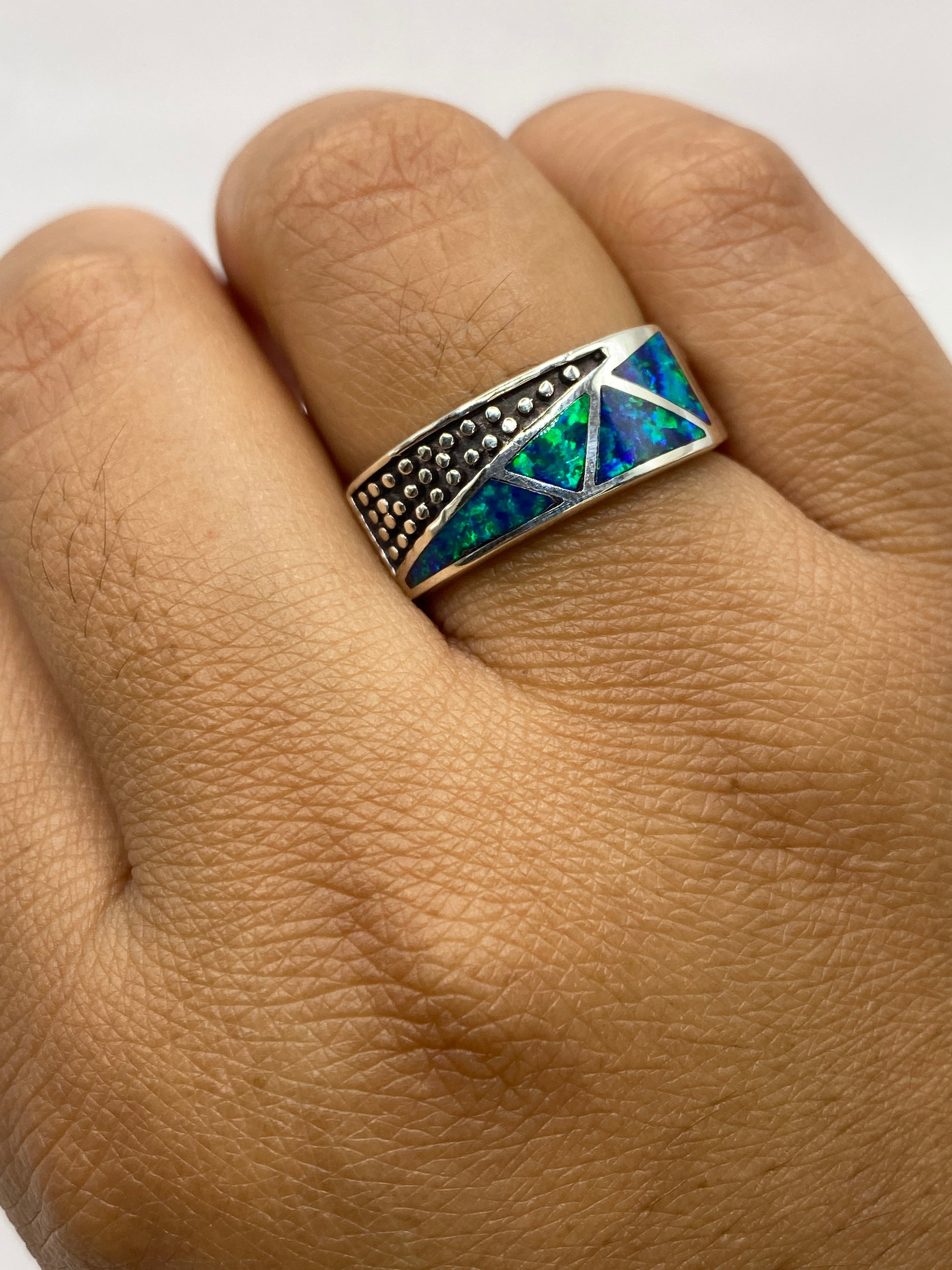 Anillo en la mano mostrando el juego de color azul y verde del ópalo de fuego