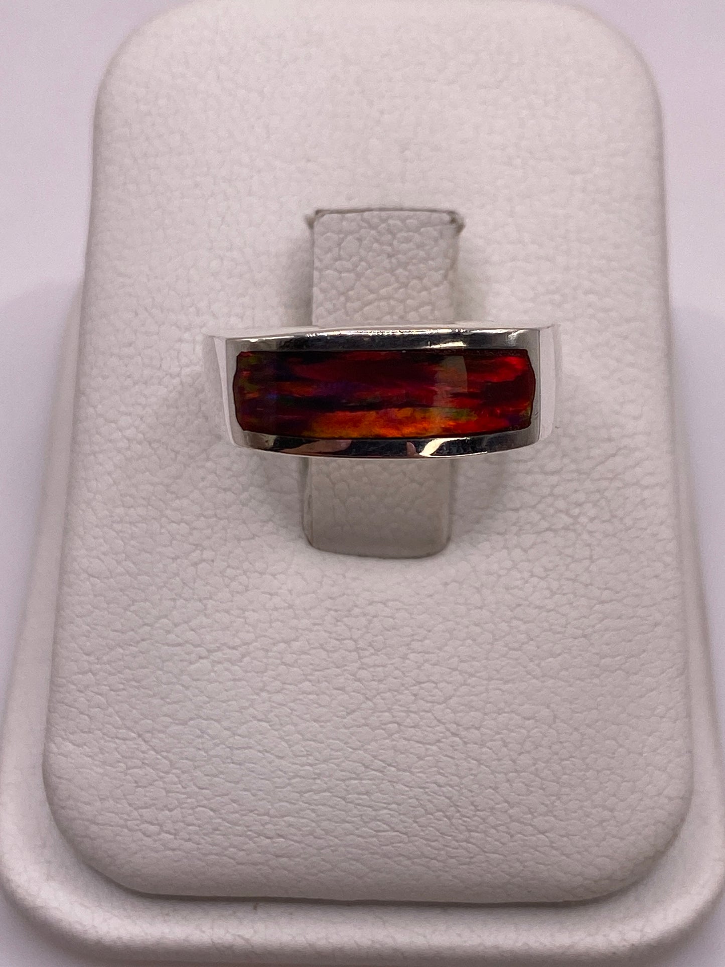 Anillo de plata .925 con ópalo de fuego multicolor en band plana, vista frontal sobre soporte blanco