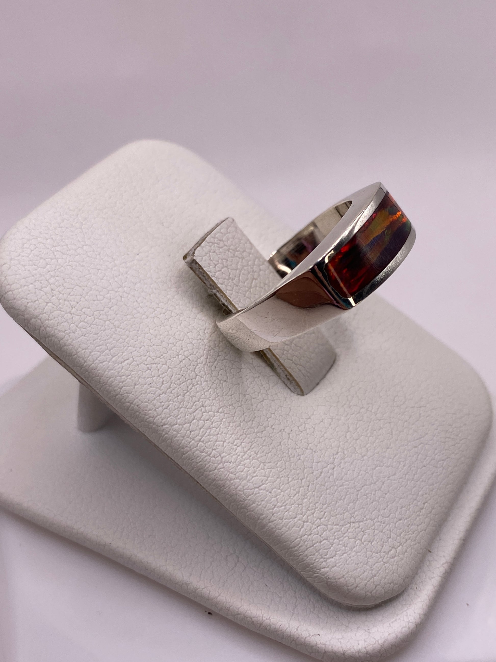 Anillo unisex de plata con ópalo natural multicolor llevado en dedo, detalle del juego de colores