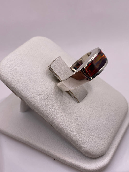 Anillo unisex de plata con ópalo natural multicolor llevado en dedo, detalle del juego de colores