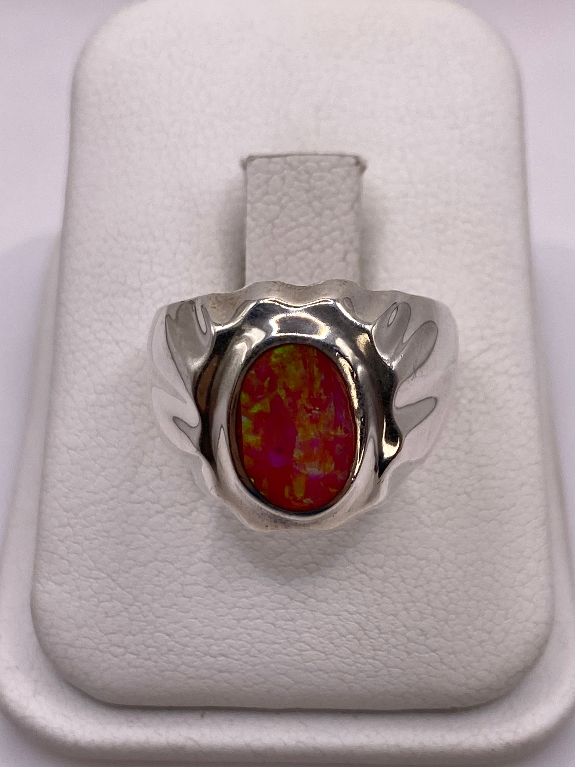 Anillo de plata con opalo de fuego rosa y alas esculpidas en la mano de una mujer