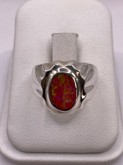 Anillo de plata con opalo de fuego rosa y alas esculpidas en la mano de una mujer