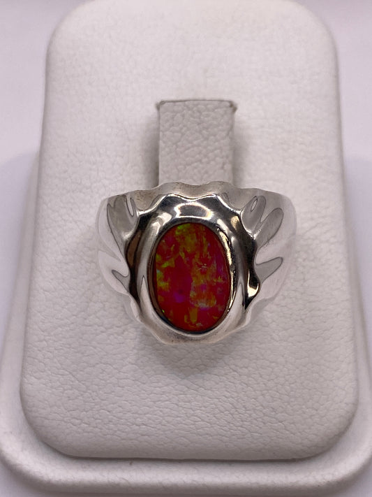Anillo de plata con opalo de fuego rosa y alas esculpidas en la mano de una mujer