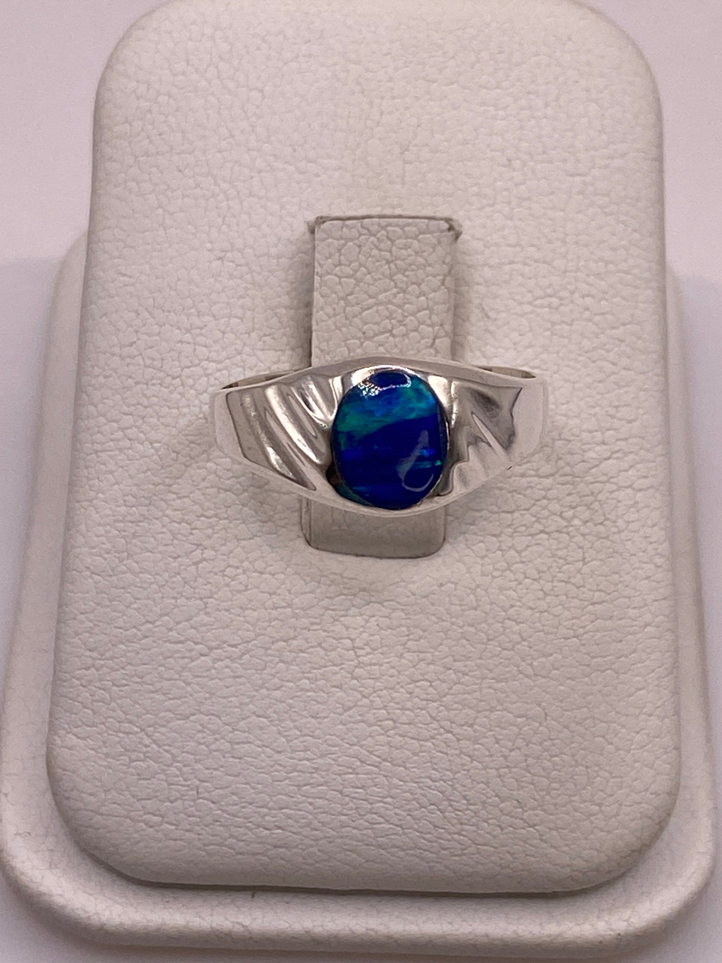 Anillo de plata solitario con ópalo de fuego azul, visto desde arriba sobre estuche blanco