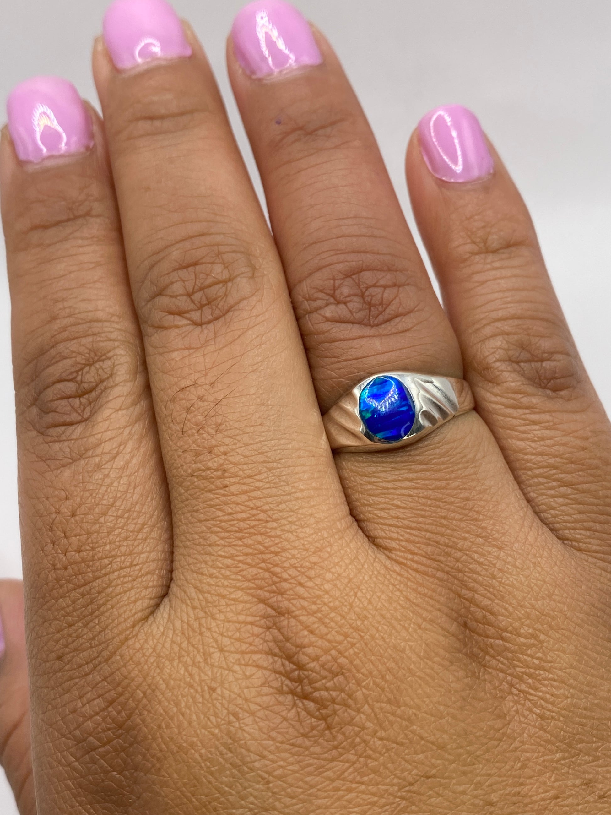Anillo en dedo mostrando color azul verdoso del ópalo de fuego bajo luz natural