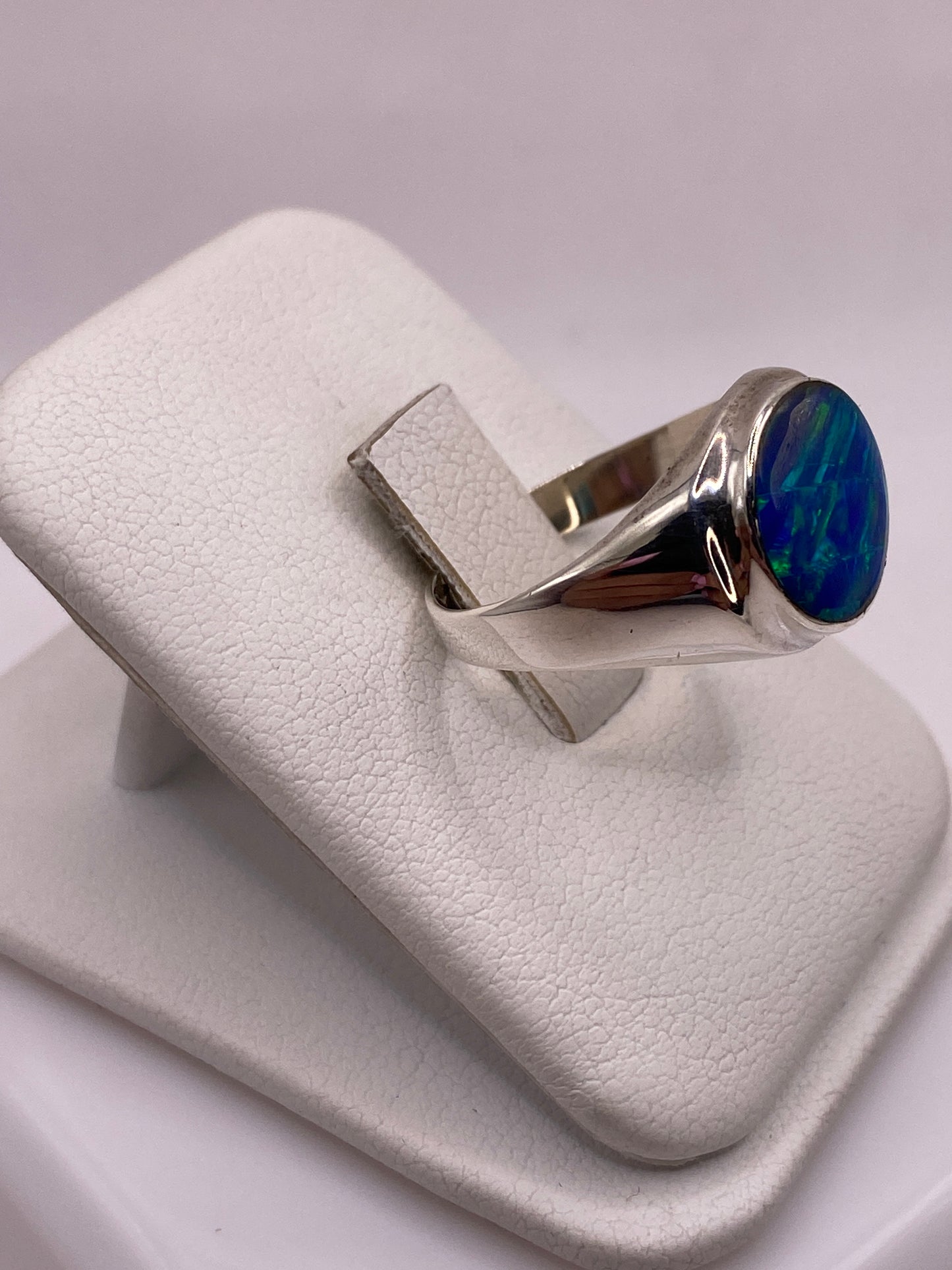 Vista frontal del anillo con ópalo de fuego mostrando juego de colores azul y verde