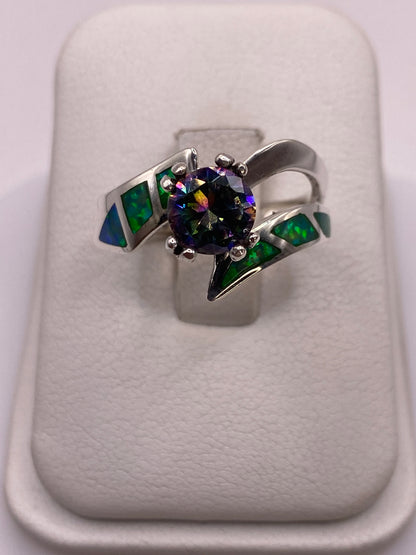 Anillo de plata .950 con ópalo de fuego verde y engastes laterales verdes en la mano