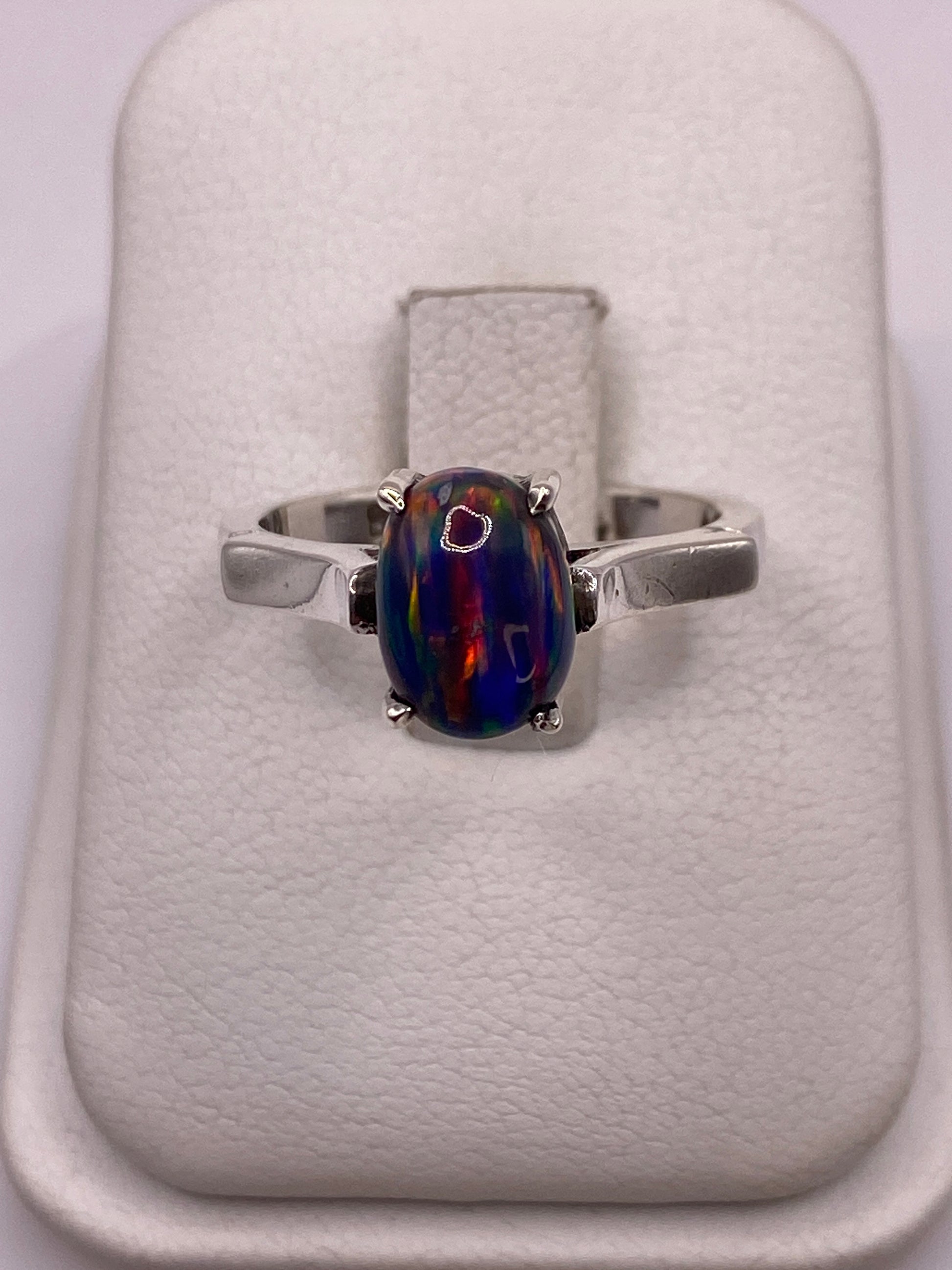 Anillo de plata .950 solitario con ópalo de fuego multicolor sobre almohada blanca