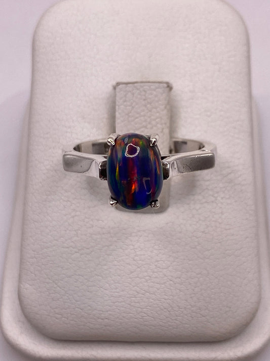 Anillo de plata .950 solitario con ópalo de fuego multicolor sobre almohada blanca