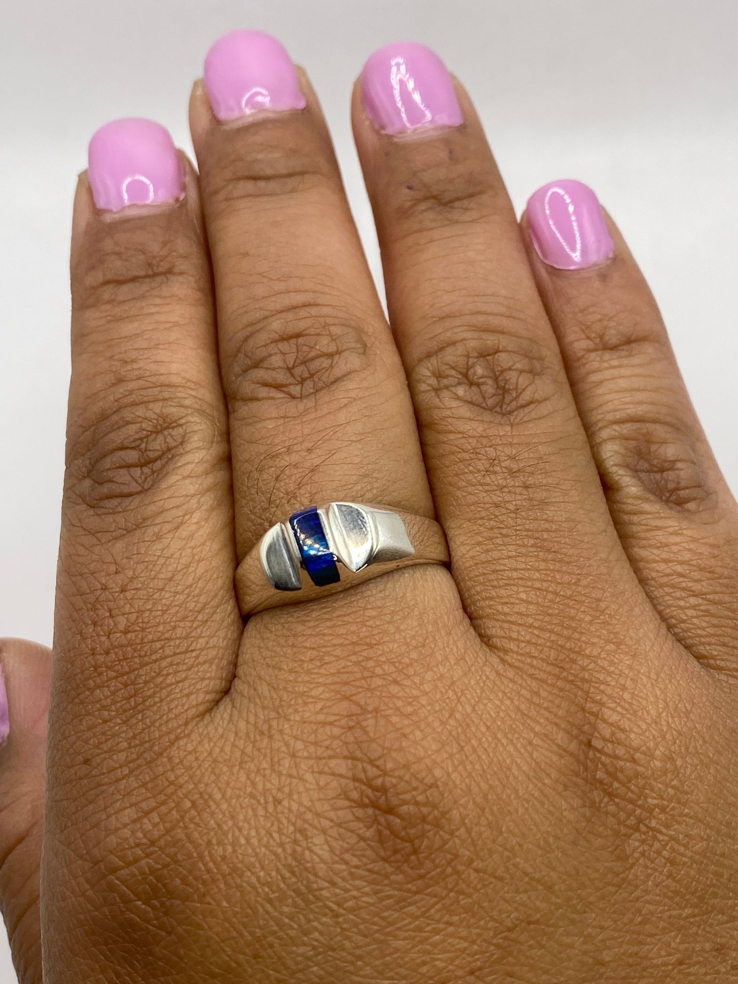 Anillo en la mano mostrando brillo y profundidad del ópalo, con sello 950 visible