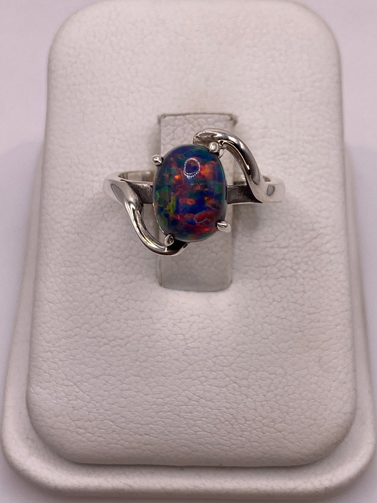 Anillo solitario de ópalo de fuego natural con engaste en plata .950, sobre peana blanca