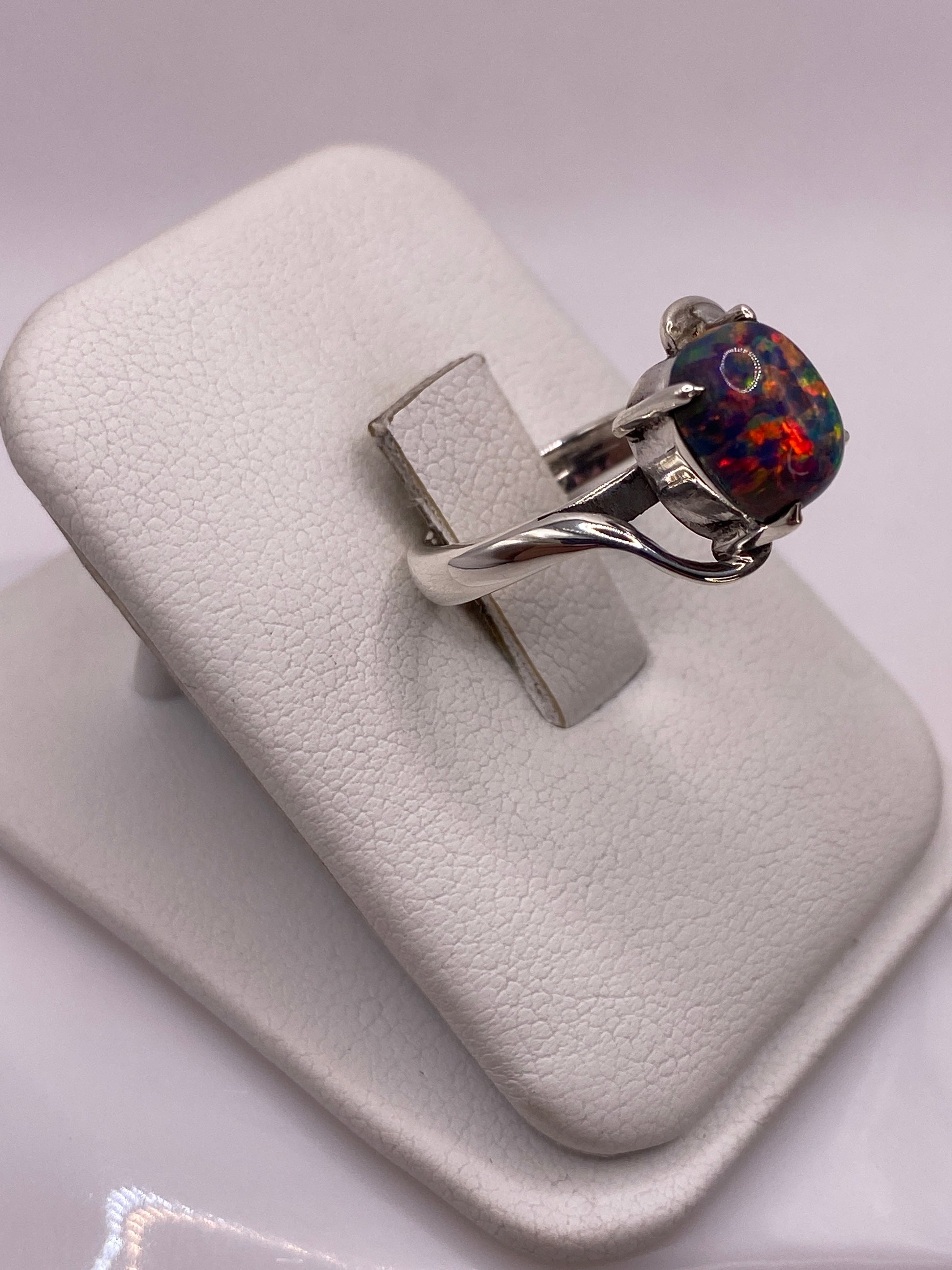 Vista lateral del anillo mostrando el juego de colores del ópalo — rojo, verde, azul y oro