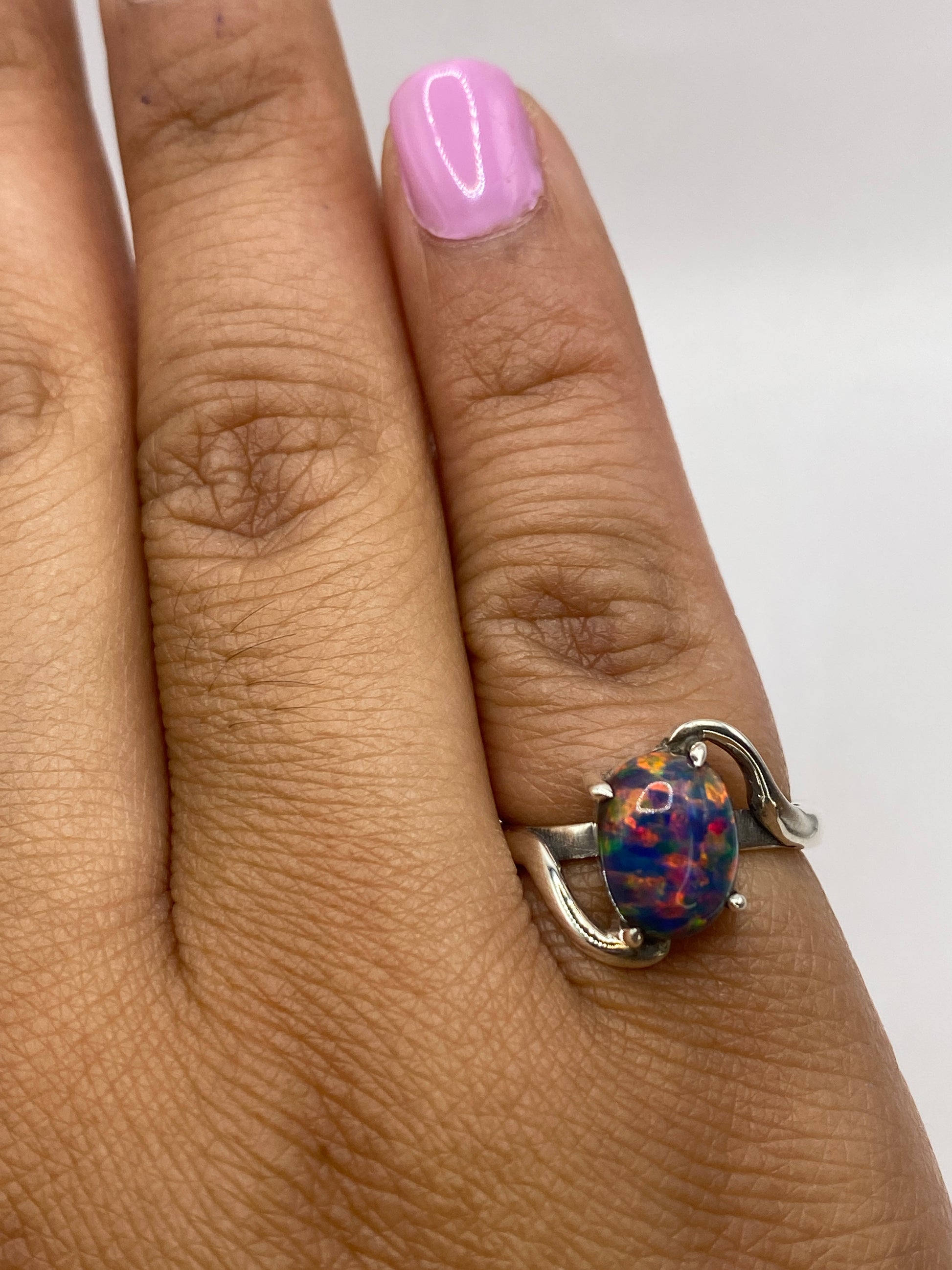 Anillo sobre dedo mostrando el brillo multicolor del ópalo bajo luz natural