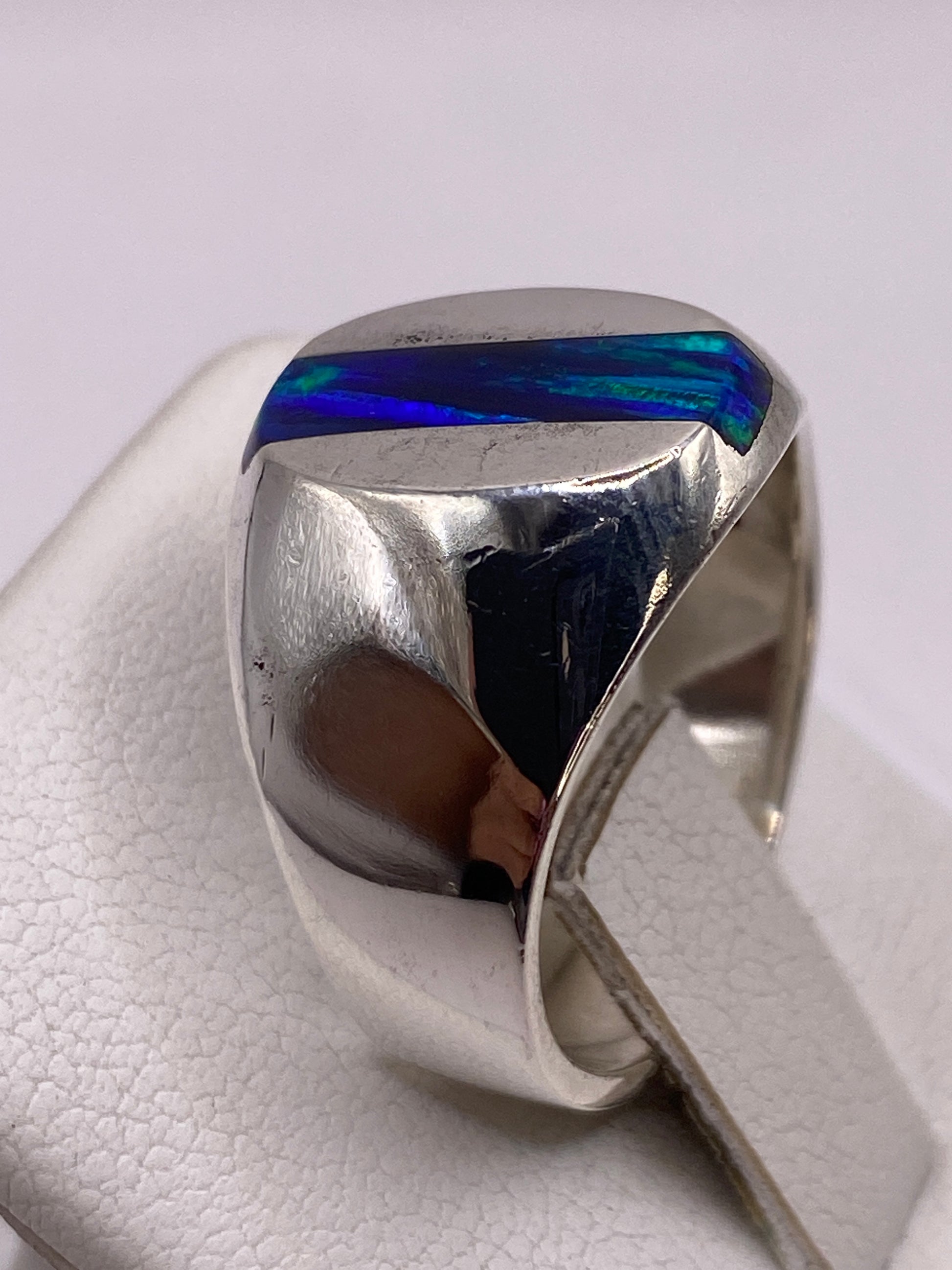 Detalle lateral del anillo en plata pulida con banda ancha y piedra engastada
