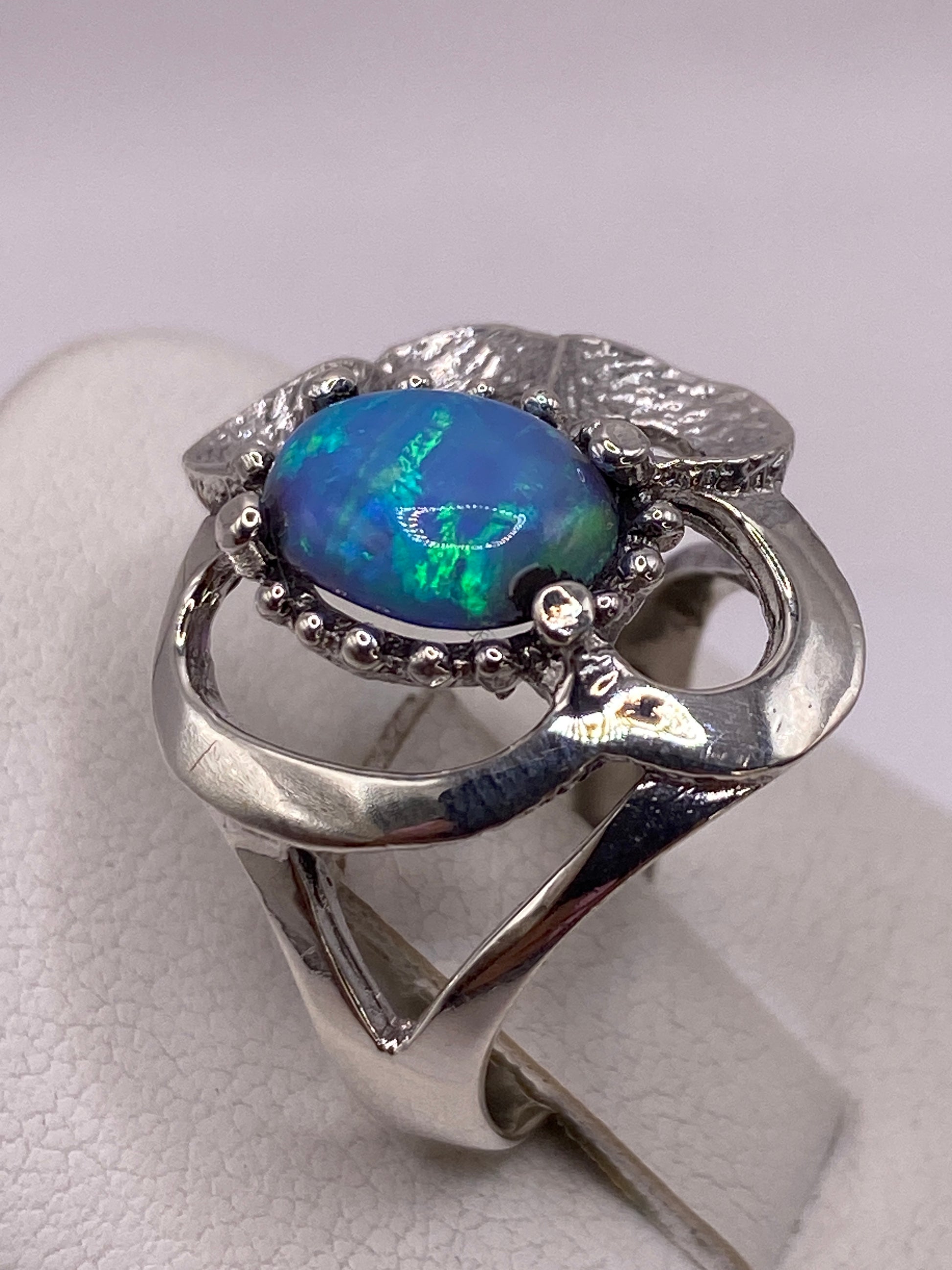 Anillo pétalo con ópalo natural azul cielo en mano de mujer